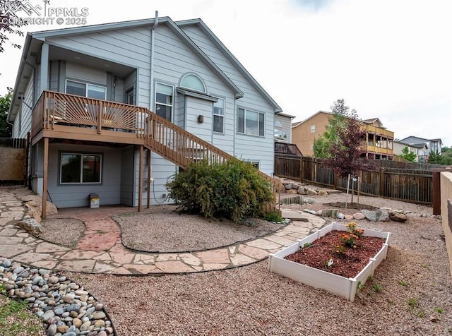 rear view of property with a patio, a vegetable garden, stairs, and fence