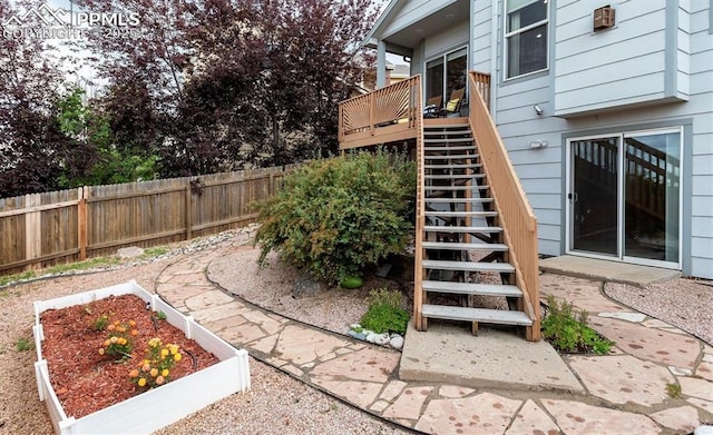 view of yard with a wooden deck, a vegetable garden, stairs, and fence