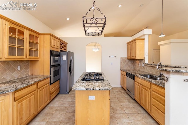 kitchen with a kitchen island, glass insert cabinets, light stone countertops, stainless steel appliances, and a sink