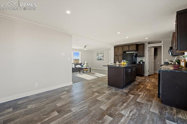 kitchen featuring dark countertops, ornamental molding, open floor plan, a center island, and black refrigerator