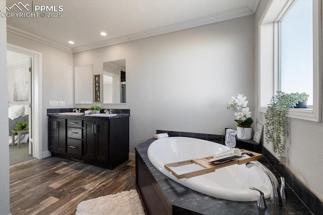 bathroom with a garden tub, double vanity, ornamental molding, and wood finished floors