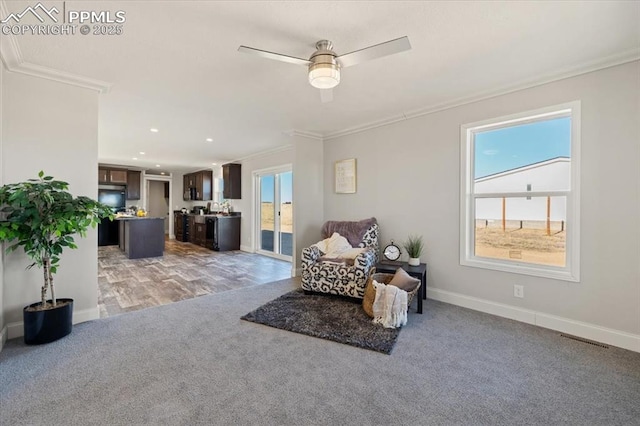 sitting room featuring baseboards, ornamental molding, a wealth of natural light, and light colored carpet