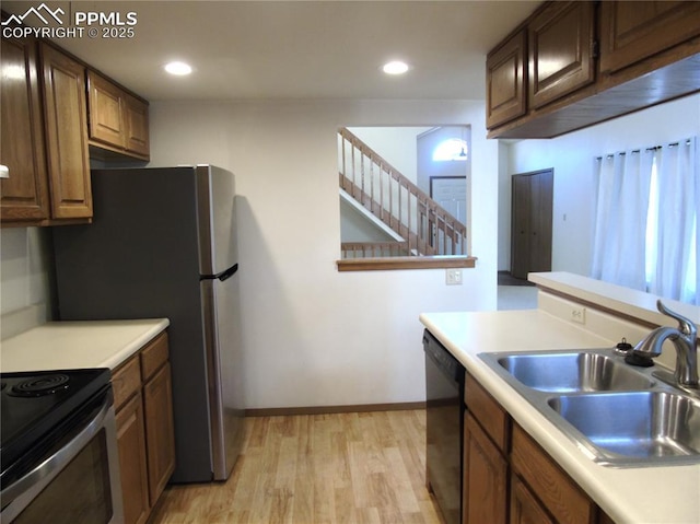 kitchen featuring light countertops, light wood-type flooring, black dishwasher, recessed lighting, and a sink