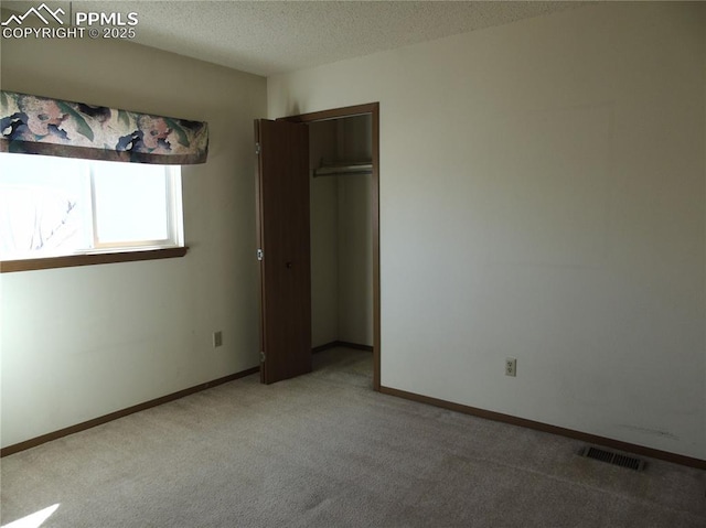 unfurnished bedroom featuring visible vents, carpet floors, a textured ceiling, and baseboards