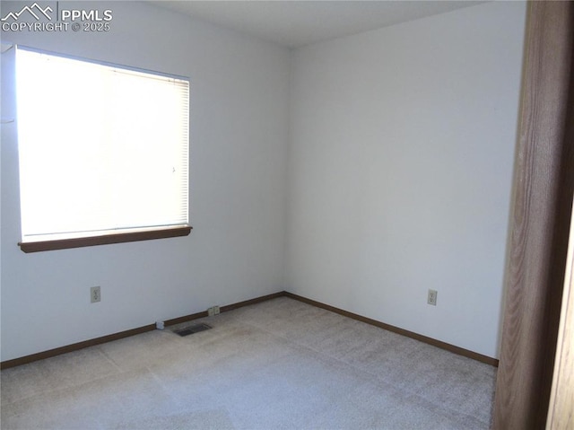 empty room featuring visible vents, light colored carpet, and baseboards