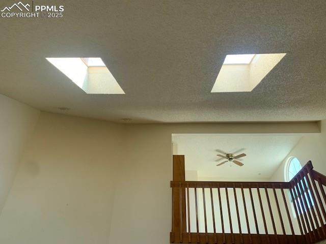 interior space featuring beamed ceiling, a textured ceiling, a skylight, and a ceiling fan