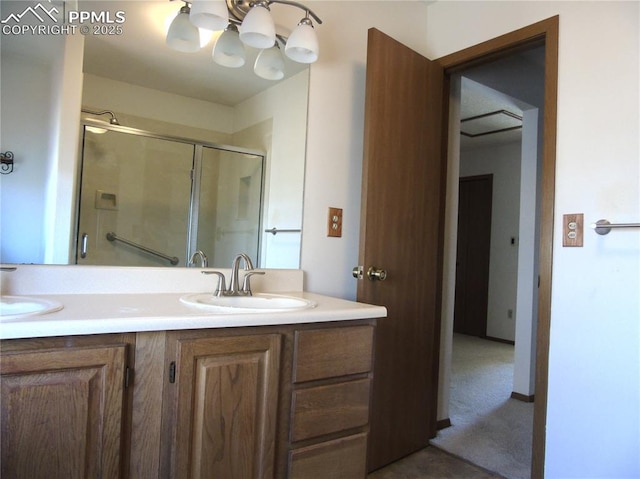 full bathroom featuring double vanity, a stall shower, a chandelier, and a sink