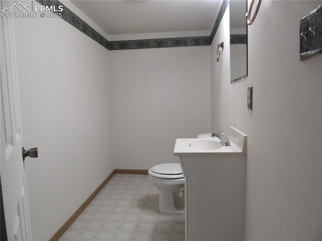 half bath featuring tile patterned floors, toilet, vanity, and baseboards