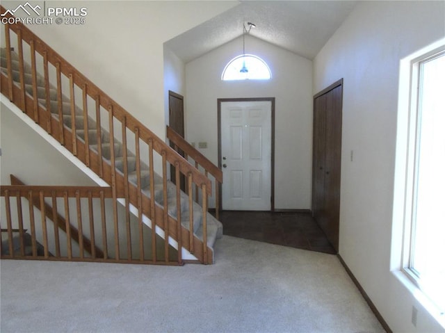 entrance foyer with vaulted ceiling, stairway, carpet, and baseboards