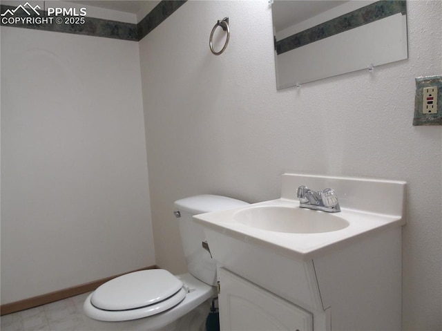 half bathroom with baseboards, toilet, and vanity