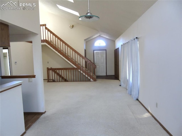 unfurnished living room featuring stairway, baseboards, high vaulted ceiling, a skylight, and carpet flooring