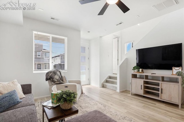 living area with a healthy amount of sunlight, visible vents, stairway, and light wood finished floors