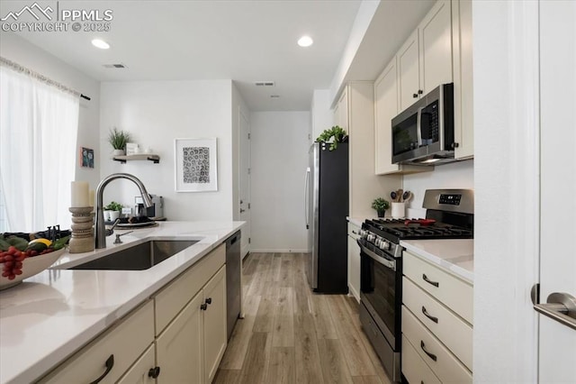 kitchen featuring stainless steel appliances, light wood-type flooring, a sink, and visible vents