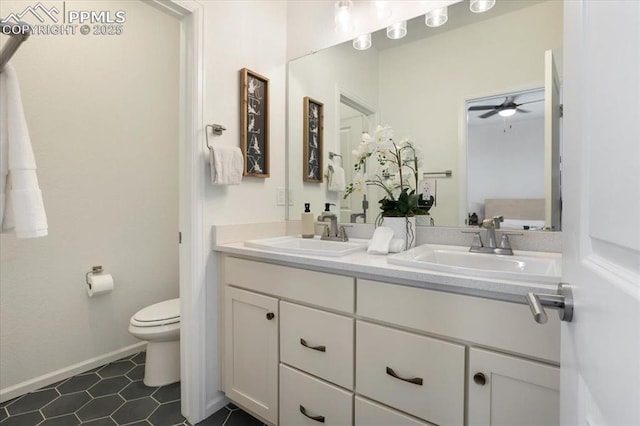 bathroom with baseboards, a sink, toilet, and double vanity