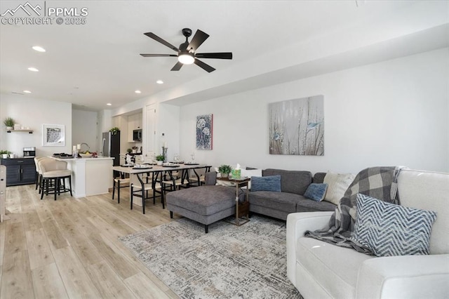 living area with light wood-type flooring, ceiling fan, and recessed lighting