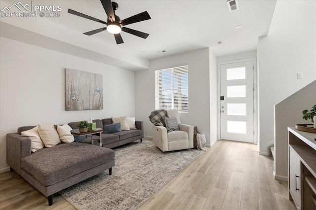 living room featuring light wood-style floors, baseboards, visible vents, and a ceiling fan