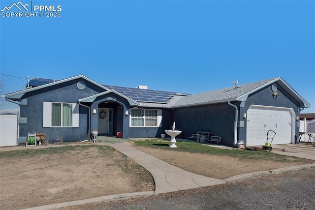 single story home with stucco siding, roof mounted solar panels, driveway, and an attached garage