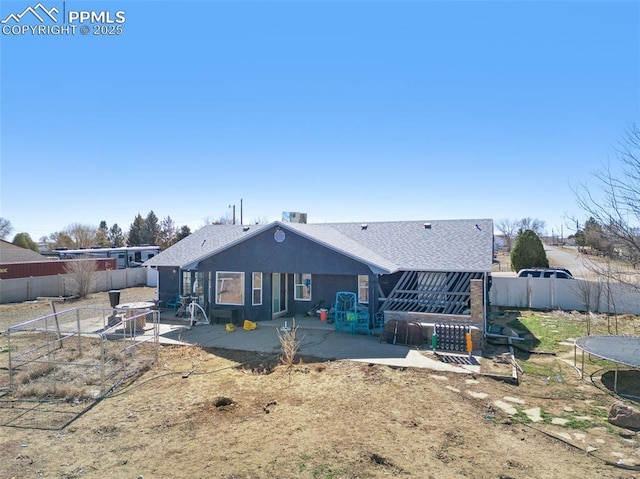 back of house with stucco siding, a trampoline, a fenced backyard, and a patio area