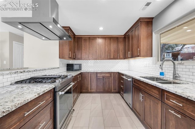 kitchen featuring visible vents, a sink, stainless steel appliances, wall chimney exhaust hood, and light stone countertops