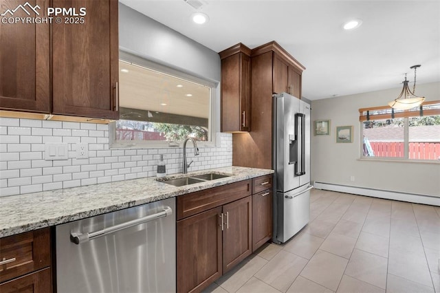 kitchen with light stone counters, a baseboard radiator, a sink, stainless steel appliances, and tasteful backsplash