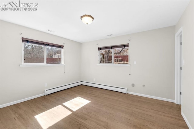 empty room featuring a baseboard radiator, baseboards, visible vents, and wood finished floors