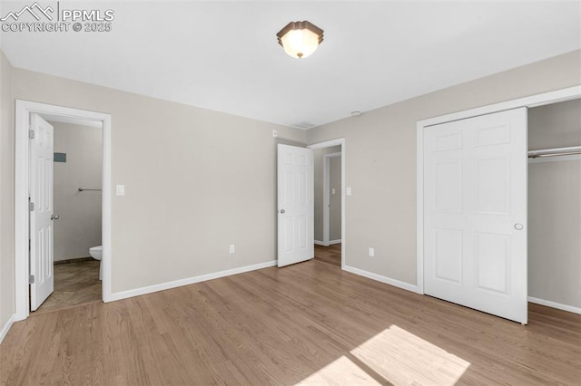 unfurnished bedroom featuring a closet, light wood-style flooring, ensuite bathroom, and baseboards