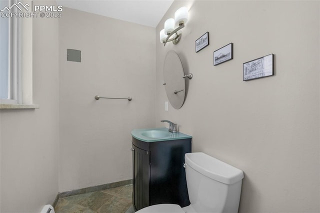 half bathroom with toilet, vanity, and baseboards