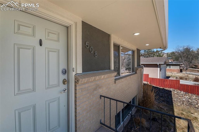 property entrance featuring brick siding and fence