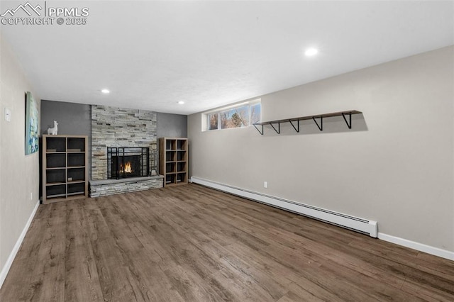 unfurnished living room featuring a baseboard heating unit, wood finished floors, a fireplace, and baseboards