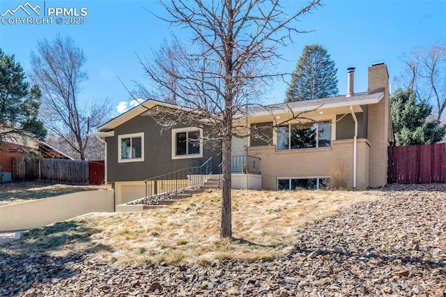 ranch-style house with brick siding, an attached garage, a chimney, and fence