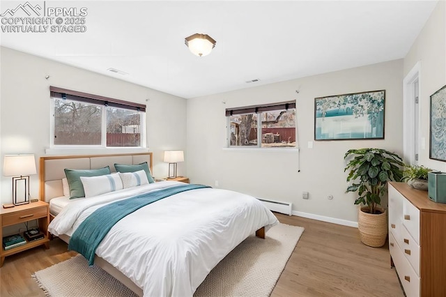 bedroom featuring visible vents, baseboards, light wood-type flooring, and baseboard heating