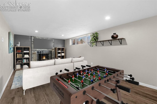 game room with a stone fireplace, recessed lighting, baseboards, and wood finished floors