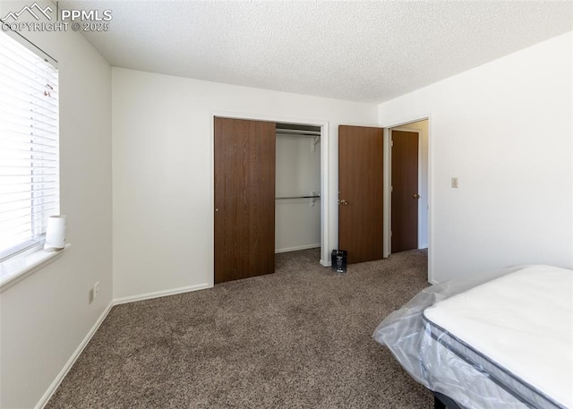 unfurnished bedroom featuring carpet floors, a closet, a textured ceiling, and baseboards