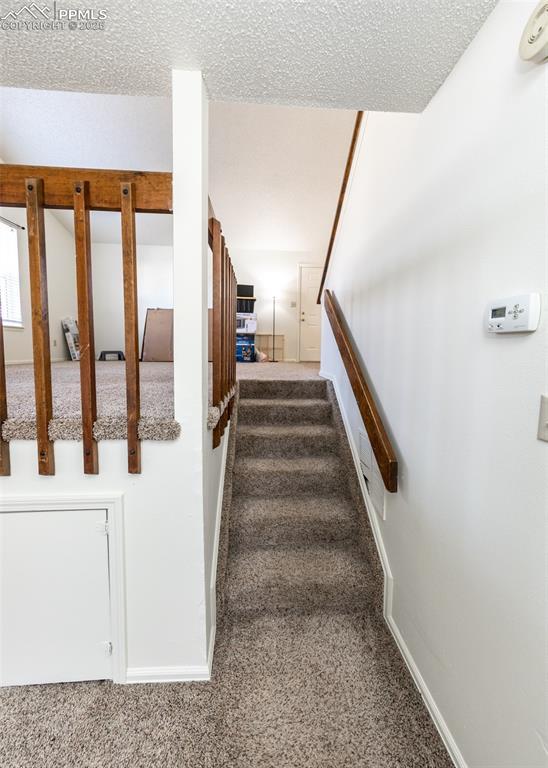 staircase with carpet, a textured ceiling, and baseboards