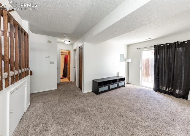 empty room with carpet floors, a textured ceiling, and baseboards