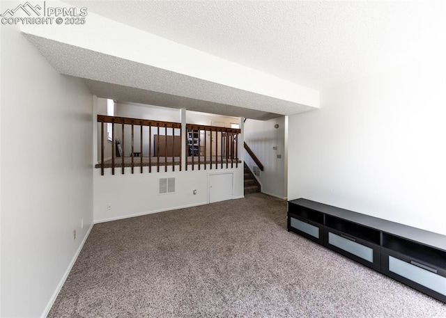 carpeted spare room featuring stairway, baseboards, visible vents, and a textured ceiling