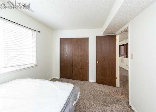 bedroom featuring a textured ceiling, carpet floors, a closet, and baseboards