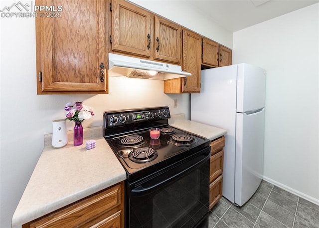 kitchen with light countertops, brown cabinetry, freestanding refrigerator, black range with electric cooktop, and under cabinet range hood