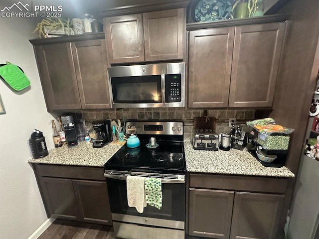 kitchen featuring dark wood-style floors, baseboards, stainless steel appliances, dark brown cabinets, and backsplash