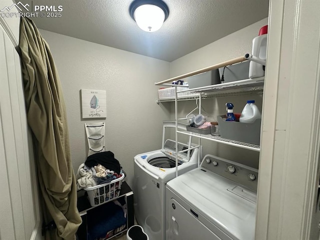 washroom with a textured ceiling, independent washer and dryer, laundry area, and a textured wall