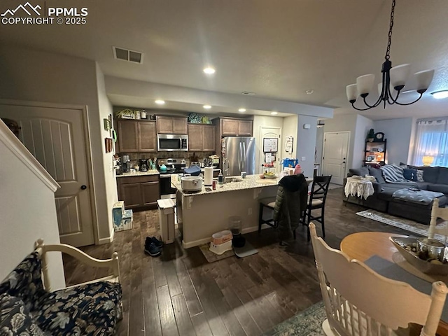 kitchen with visible vents, open floor plan, a breakfast bar, stainless steel appliances, and dark wood-style flooring