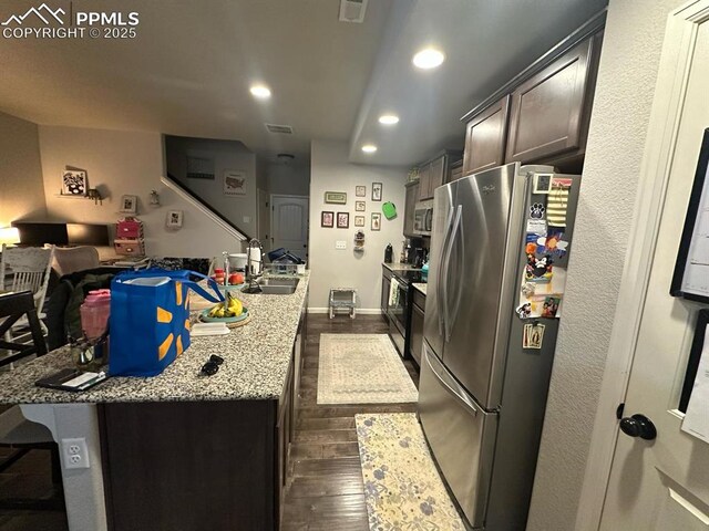 kitchen with a sink, dark wood finished floors, recessed lighting, appliances with stainless steel finishes, and light stone countertops