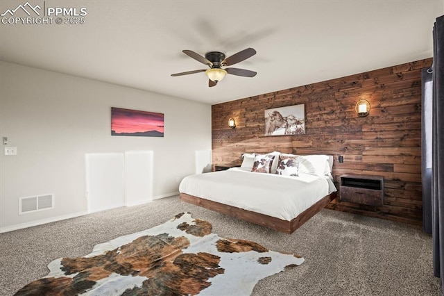 bedroom featuring wood walls, carpet, visible vents, and a ceiling fan