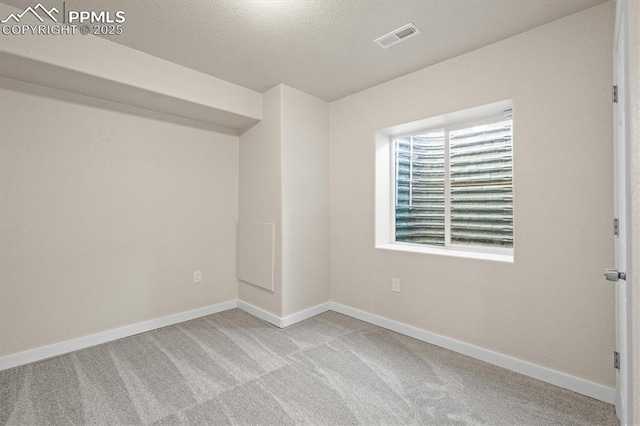 carpeted empty room with a textured ceiling, visible vents, and baseboards