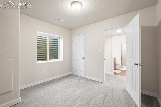 unfurnished bedroom with baseboards, a textured ceiling, visible vents, and carpet flooring