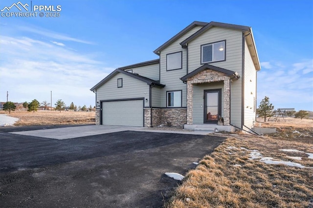 view of front of house with driveway, stone siding, and an attached garage