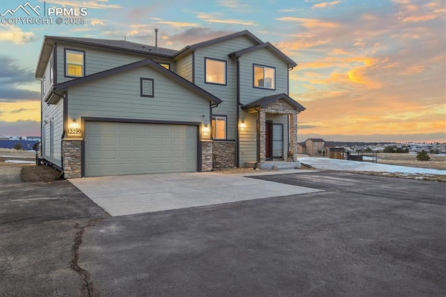 view of front of property with an attached garage, concrete driveway, and stone siding