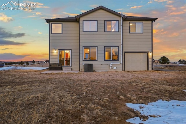 rear view of house featuring an attached garage and central AC unit