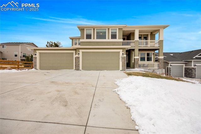 view of front of home with stucco siding, fence, a balcony, a garage, and driveway