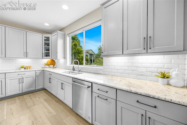 kitchen featuring recessed lighting, a sink, light wood-style floors, stainless steel dishwasher, and backsplash